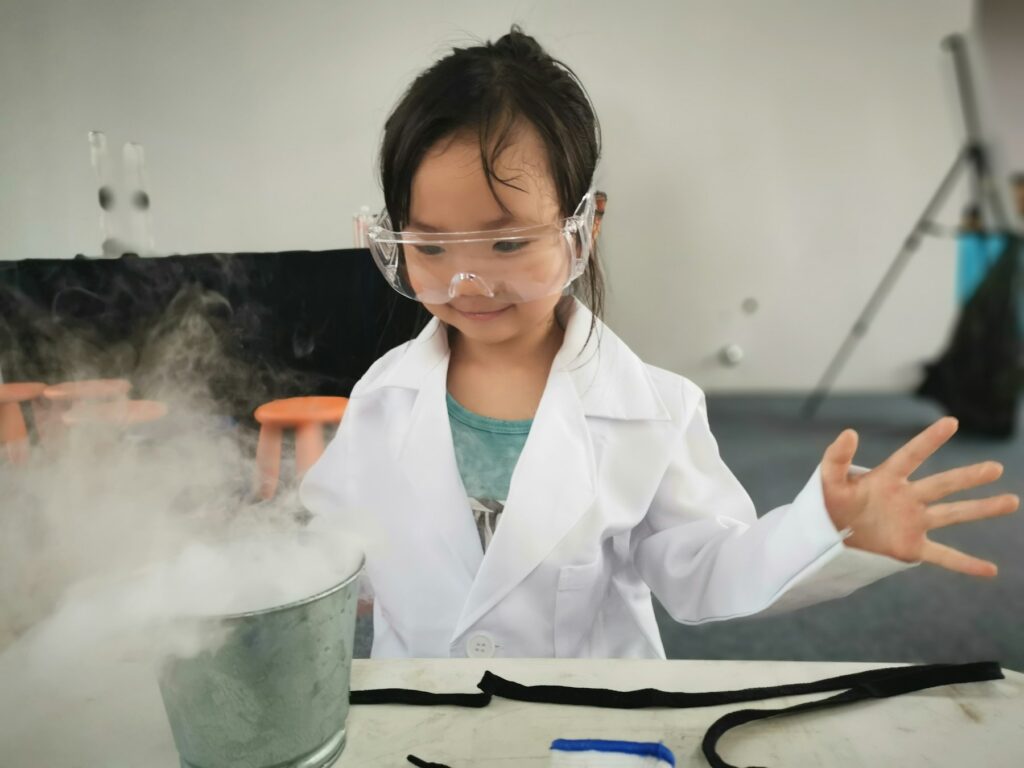 A young girl in a lab coat and safety goggles ready for an experiment